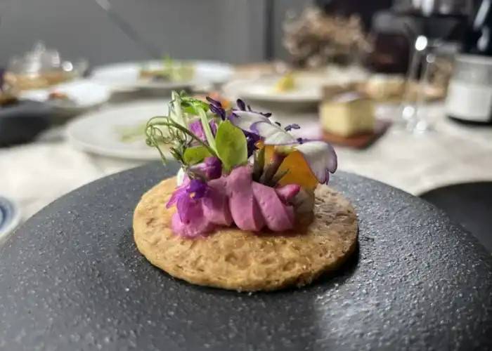 A picturesque dish at BELLA PORTO, showing off a vegan appetizer with a floral garnish, resting on a stone serving plate.
